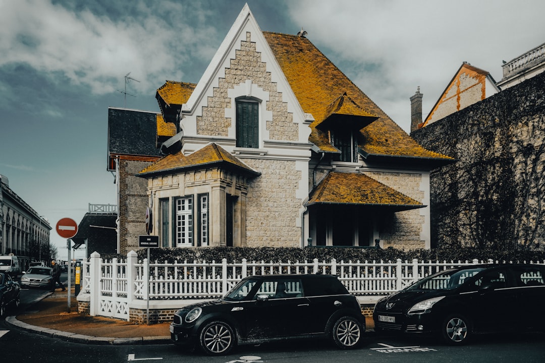 a-house-with-a-white-picket-fence-and-cars-parked-in-front-of-it-ynksrnzdfvk